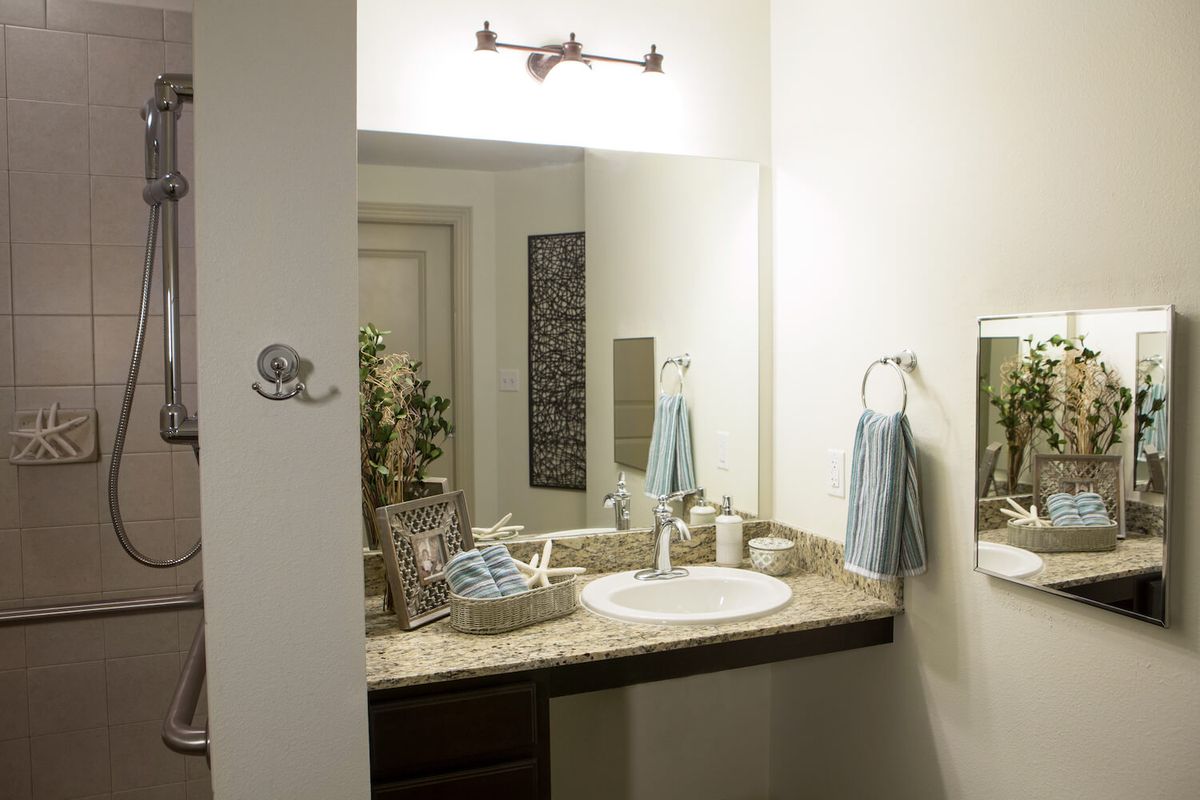 A clean and neatly decorated bathroom with a sink, mirror, and towels.