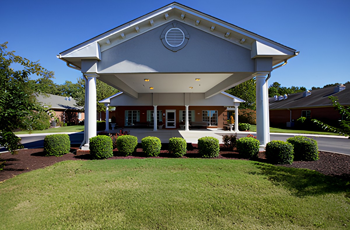 A well-maintained building entrance with columns and a neatly trimmed lawn.