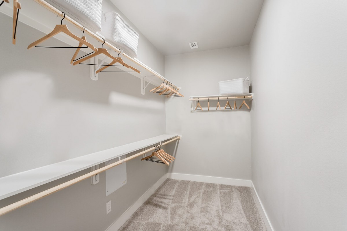 Empty walk-in closet with shelves and hangers.
