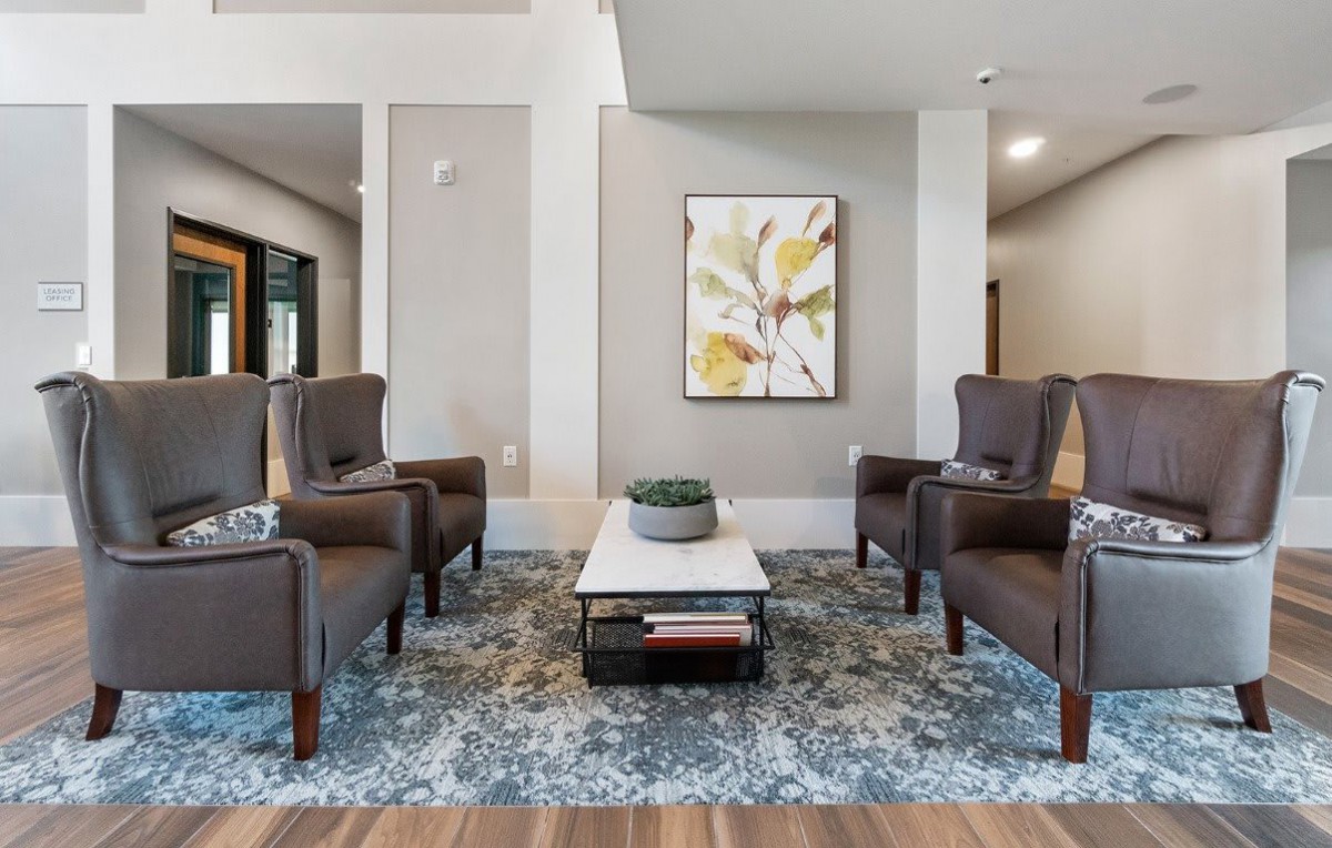 A modern living room with armchairs, a coffee table, and a decorative rug.