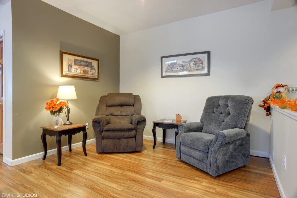 A cozy living room with two plush armchairs, warm lighting, and decorative wall art.