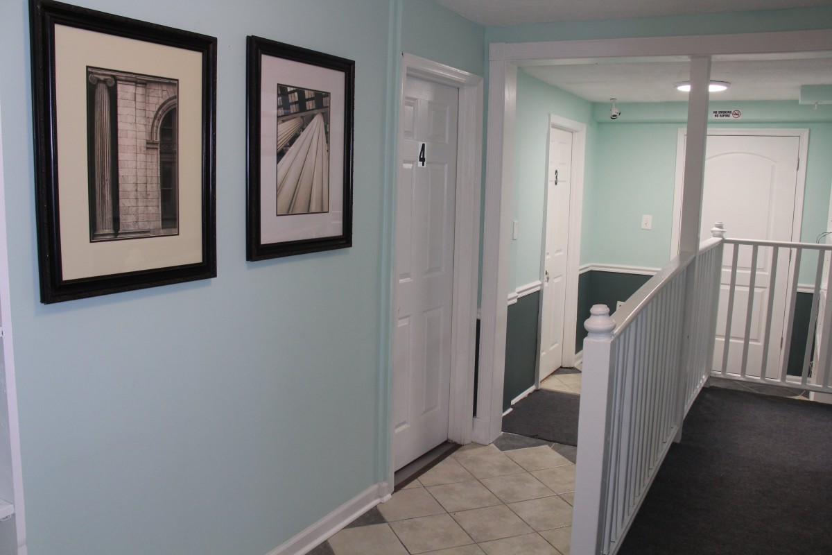 A bright hallway with framed pictures and multiple doors leading to different rooms.