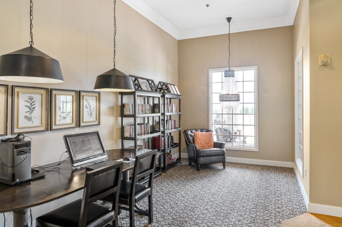 A modern home office with a desk, bookshelves, and a comfortable chair by the window.