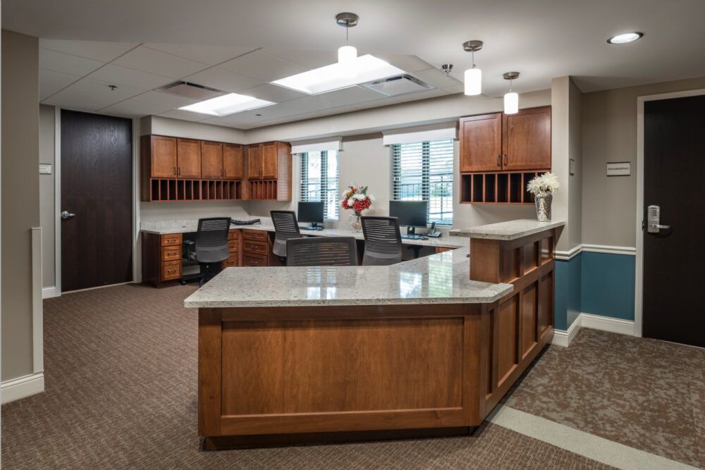 A well-lit office space with a wooden reception desk and chairs.