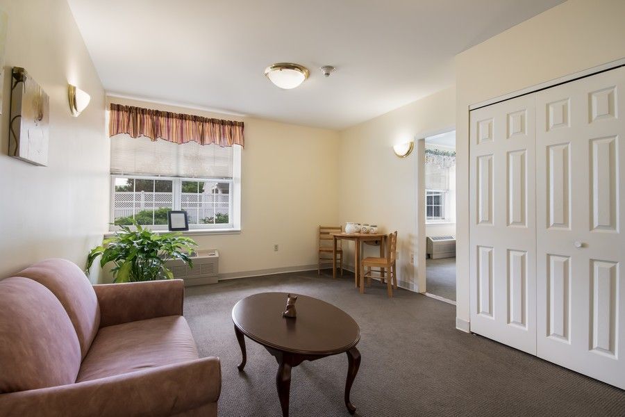 A cozy living room with a sofa, coffee table, and a large window providing natural light.