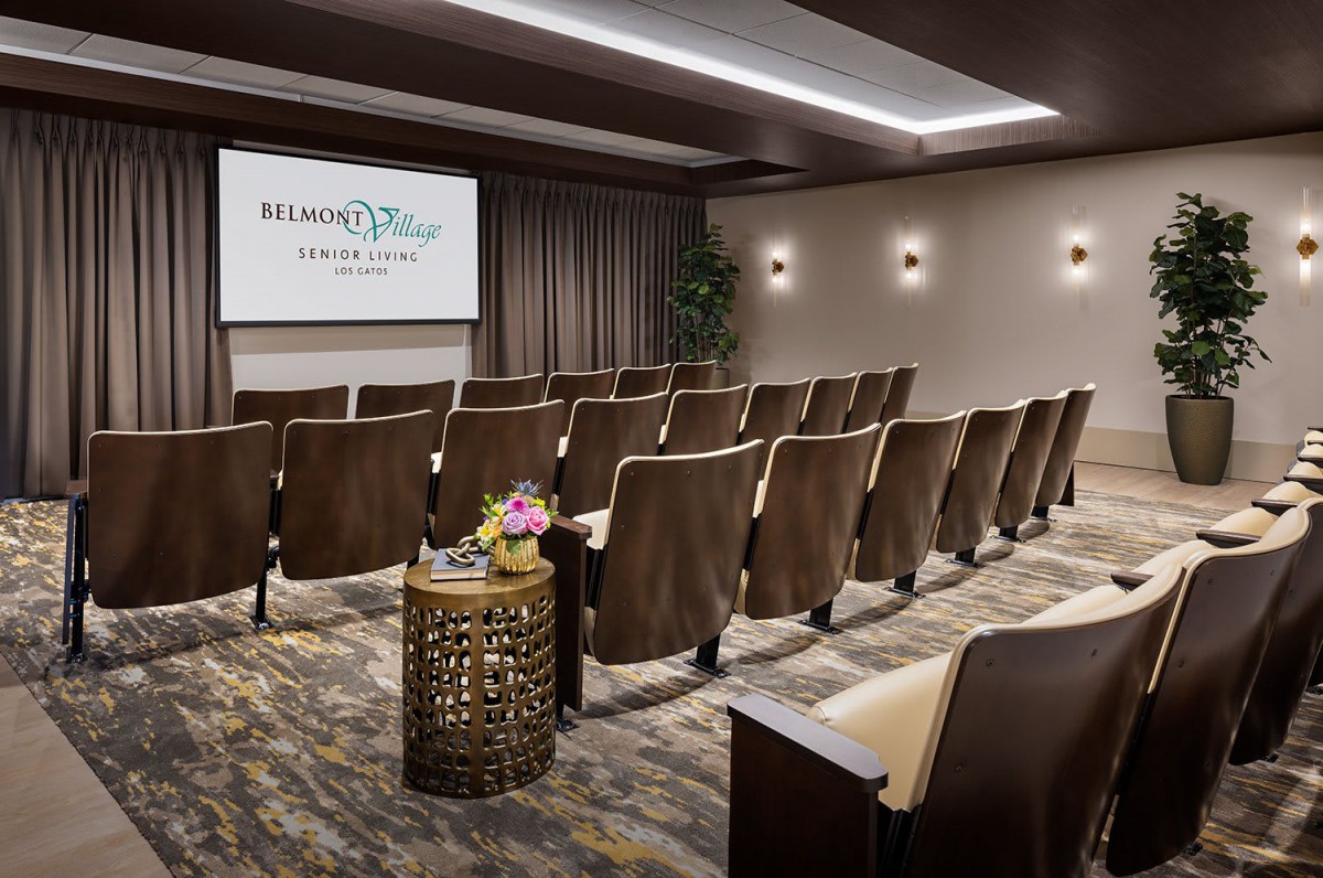 A well-furnished conference room with rows of seating facing a presentation screen.