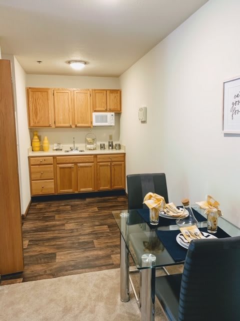 A cozy kitchen and dining area with wooden cabinets and a neatly set dining table ready for a meal.