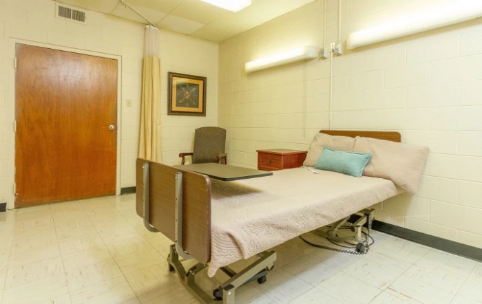 A clean and well-organized hospital room with a single bed and medical equipment.