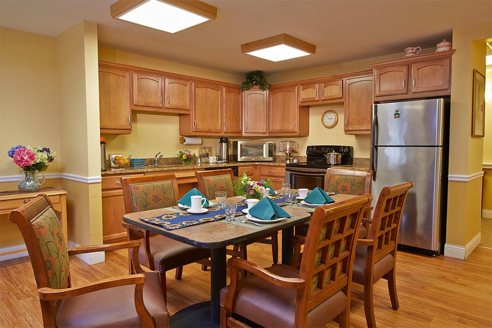A modern kitchen with a dining table set for a meal, featuring wood cabinets and stainless steel appliances.