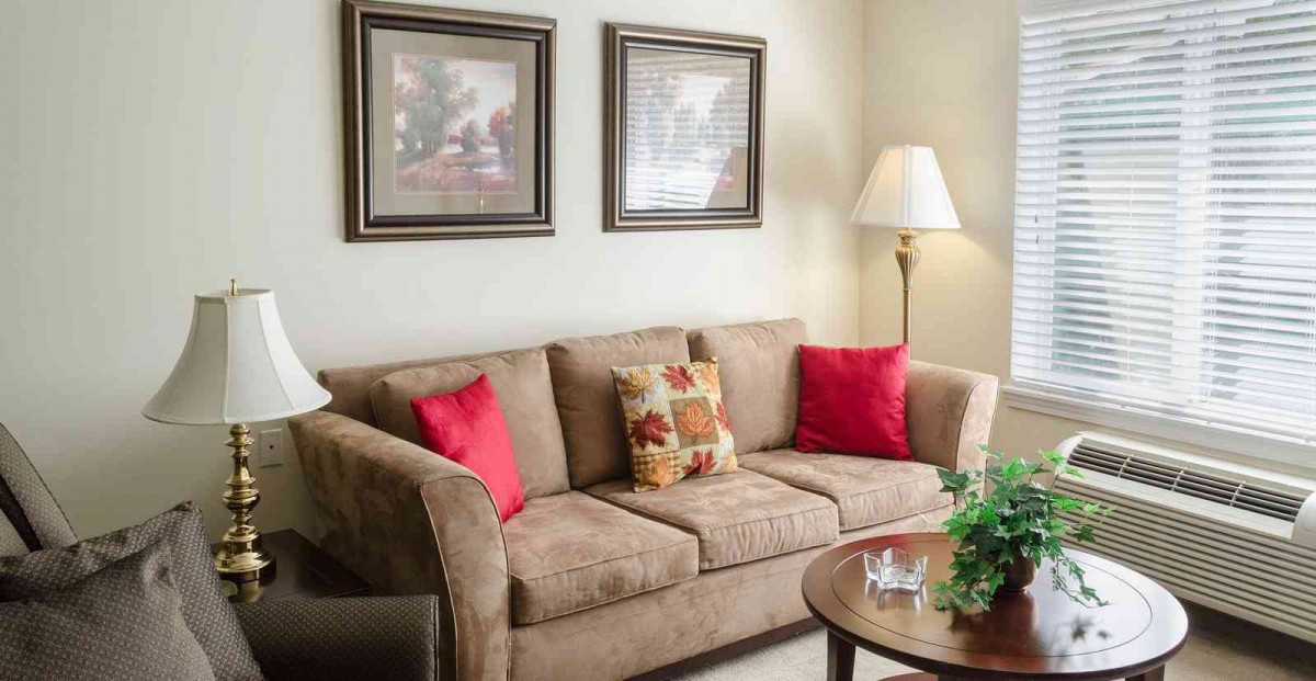 A cozy living room with a plush sofa adorned with colorful cushions, complemented by wall art and a warm floor lamp.
