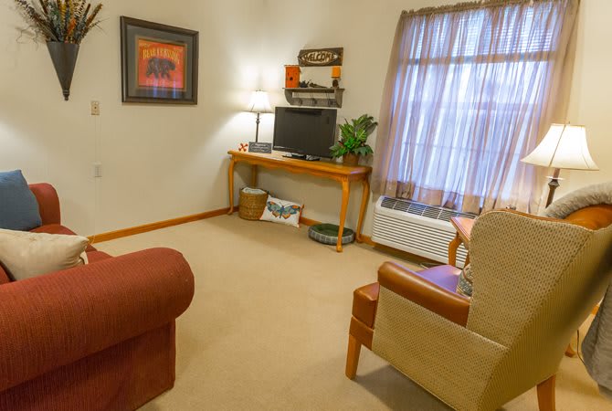 A cozy living room with a TV, lamp, and comfortable seating.