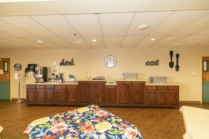 A self-service buffet area with a coffee station and decorative elements on the wall.