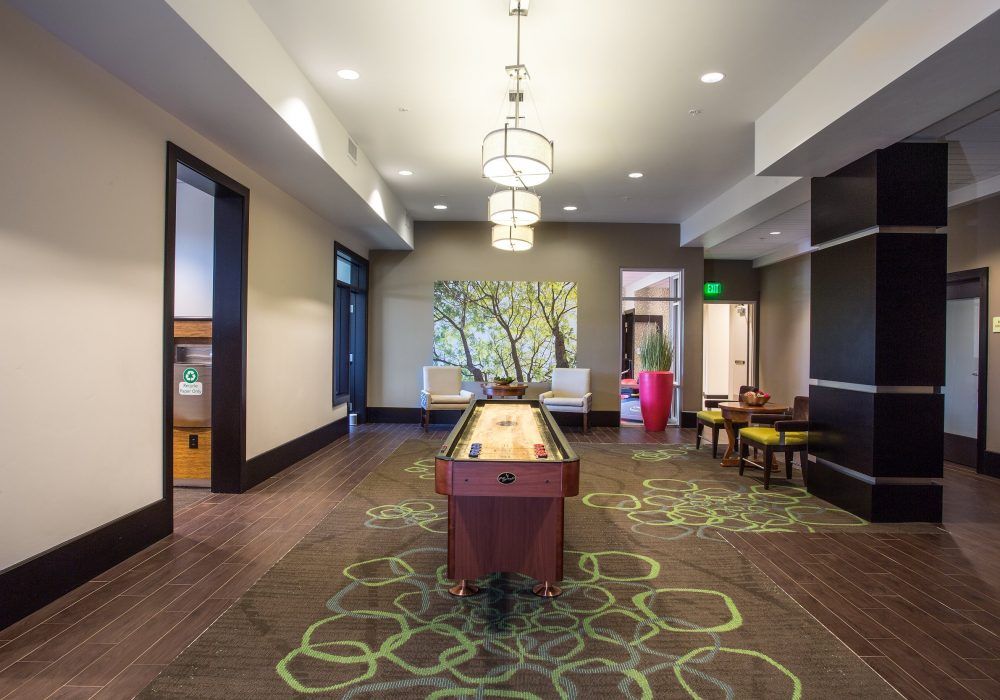 A modern recreation room featuring a shuffleboard table and stylish decor.