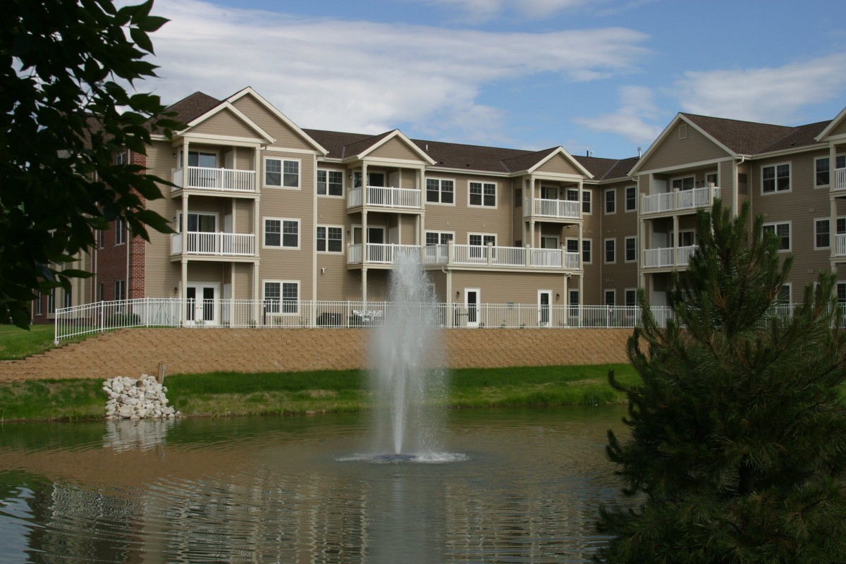 A residential apartment building with a pond and fountain in the foreground.