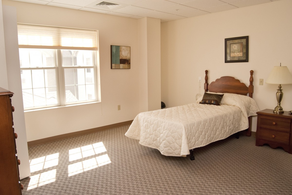 A minimalist bedroom with a single bed and decorative art on the walls.