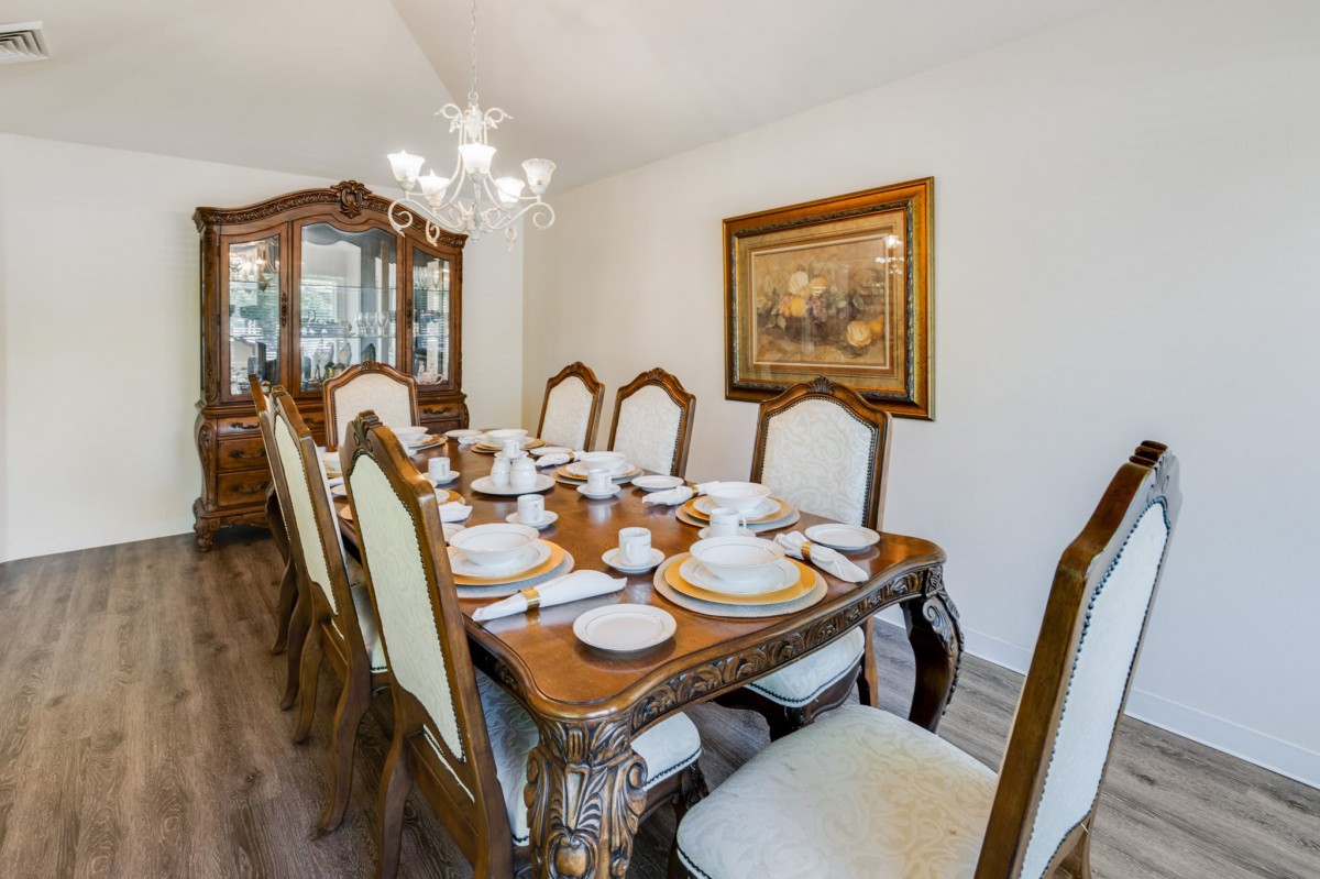 Elegant dining room setup with a richly decorated table, chandelier, and classic china cabinet.