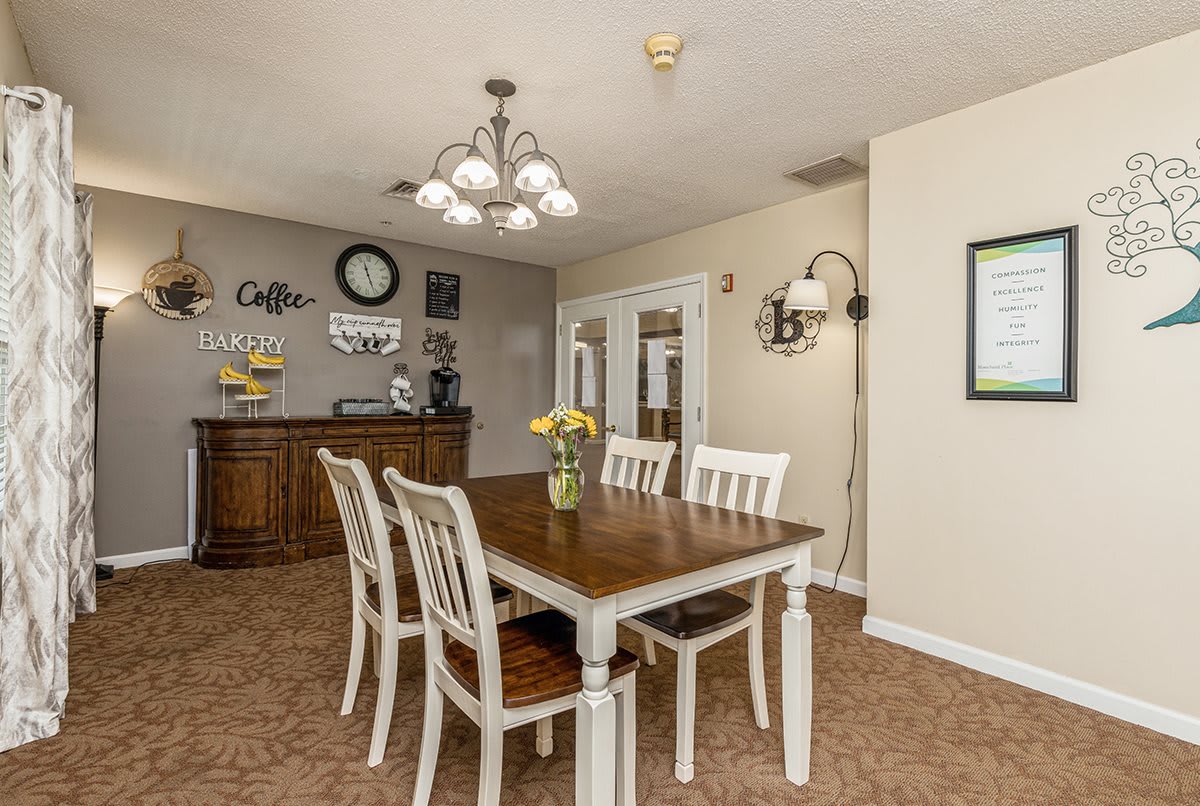 A cozy dining room with a wooden table, white chairs, and decorative elements on the walls.
