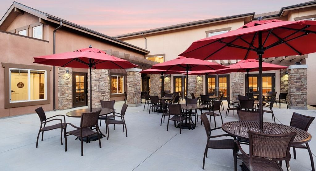 Outdoor patio area of a restaurant with red umbrellas at sunset.