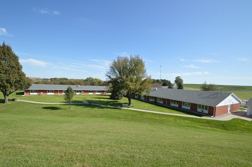 A serene view of a community building surrounded by lush greenery and a clear blue sky.
