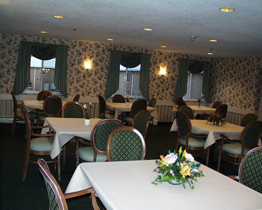 A spacious and elegantly arranged dining room featuring tables set for guests, adorned with floral centerpieces.