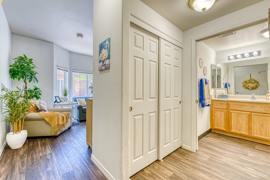 A view of an apartment interior showing a hallway with doors, leading to a living room and bathroom.