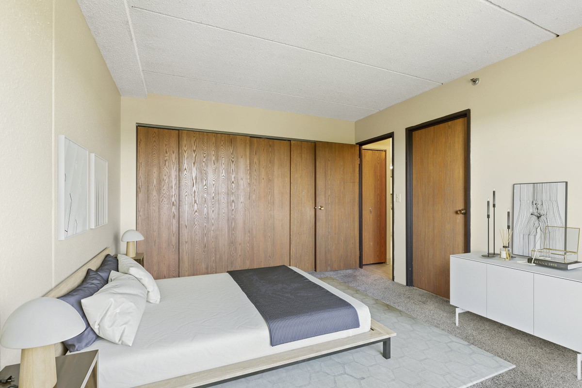 A minimalist bedroom with modern furniture and wooden wardrobes.