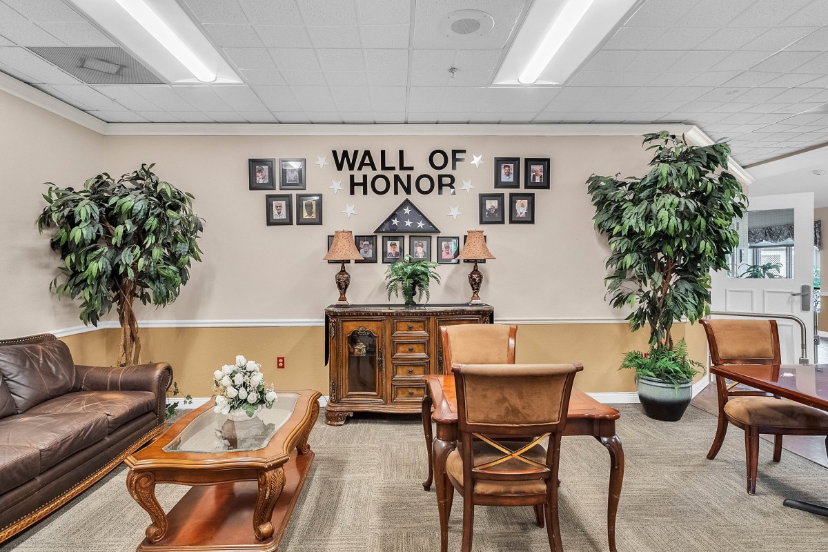A room showcasing a 'Wall of Honor' with framed portraits, decorative furniture, and potted plants.