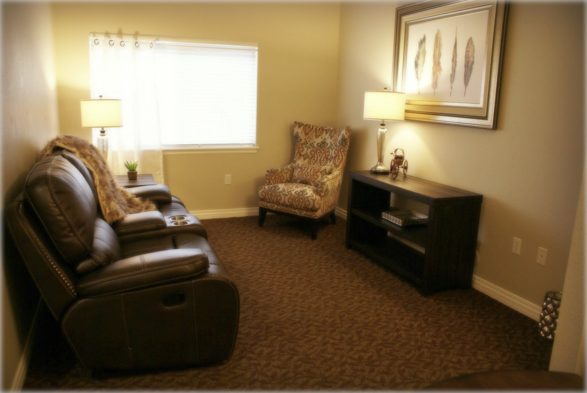 A cozy living room with a comfortable chair, lamps, and a decorative painting.