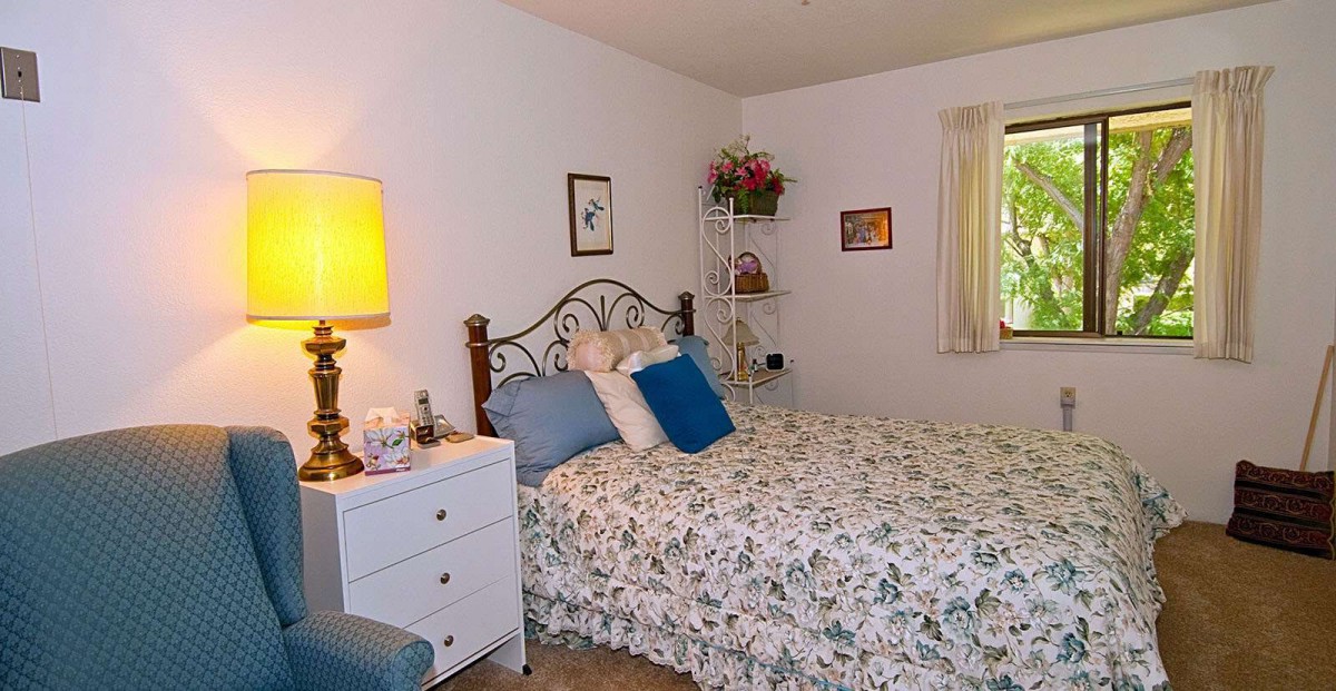 A cozy bedroom featuring a floral-patterned bedspread and warm lighting.