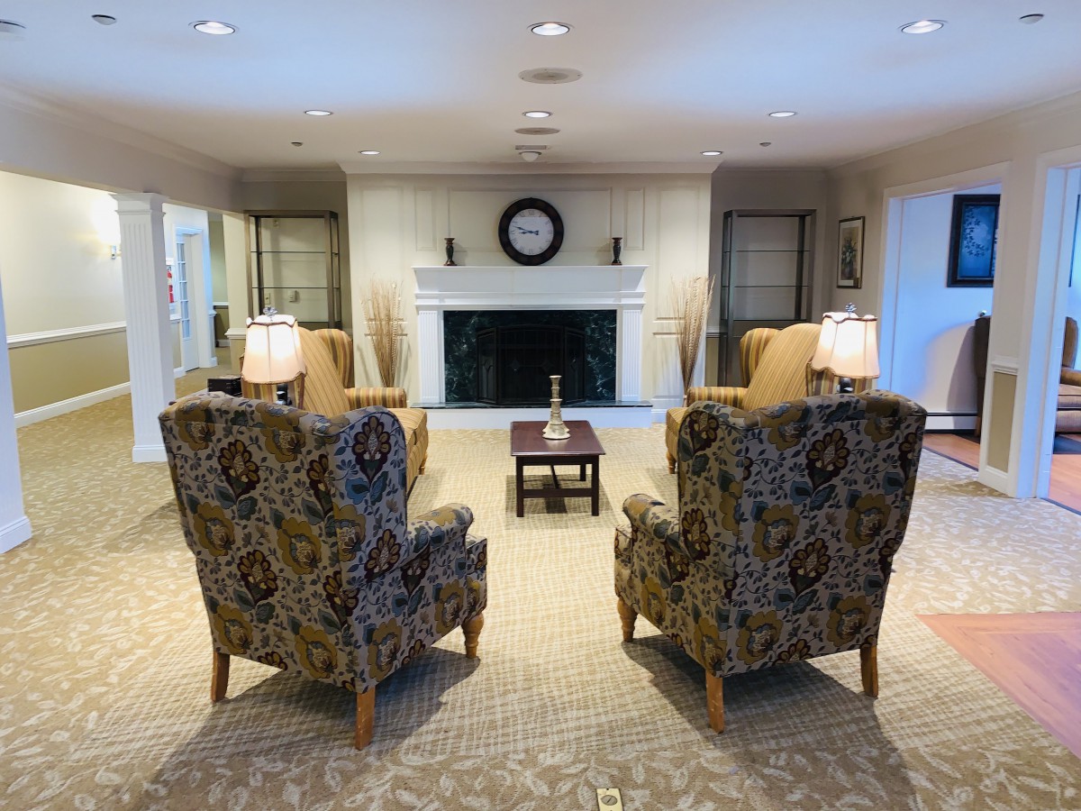 A cozy living room with patterned armchairs facing a fireplace, accented by warm lighting and decorative elements.