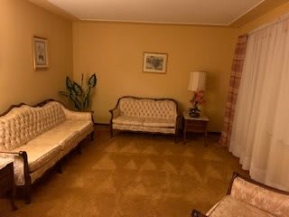 A vintage-style living room with classic sofas, a lamp, and decorative elements.