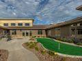 A modern building with well-maintained landscaping and a small putting green in the front yard.