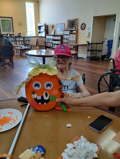 A joyful crafting session at the senior center, featuring a colorful pumpkin creation.