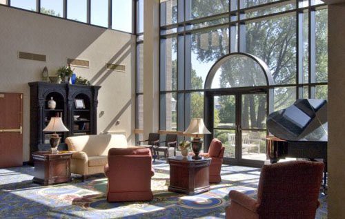 A spacious and modern lobby with large windows allowing abundant natural light, featuring comfortable seating and elegant decor.