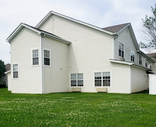 A modern two-story house with white siding and a green lawn.