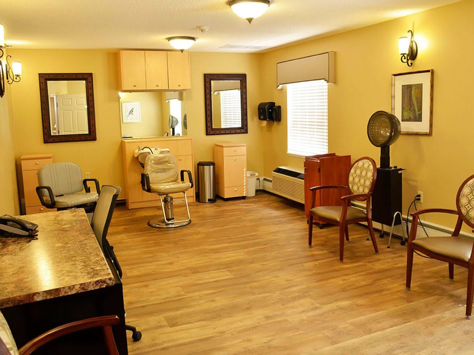 A cozy hair salon with wooden flooring, mirrors, and comfortable seating.