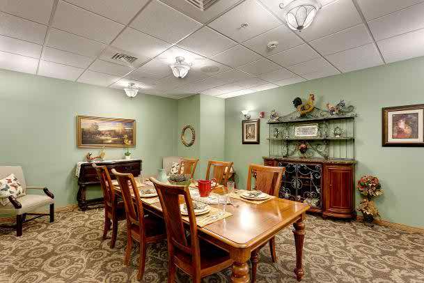 A well-decorated dining room with a wooden table and chairs, set for a meal. The room features artwork on the walls, a sideboard, and elegant lighting fixtures.