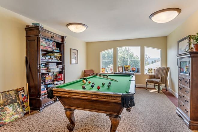 A cozy game room featuring a pool table and a well-stocked bookshelf.