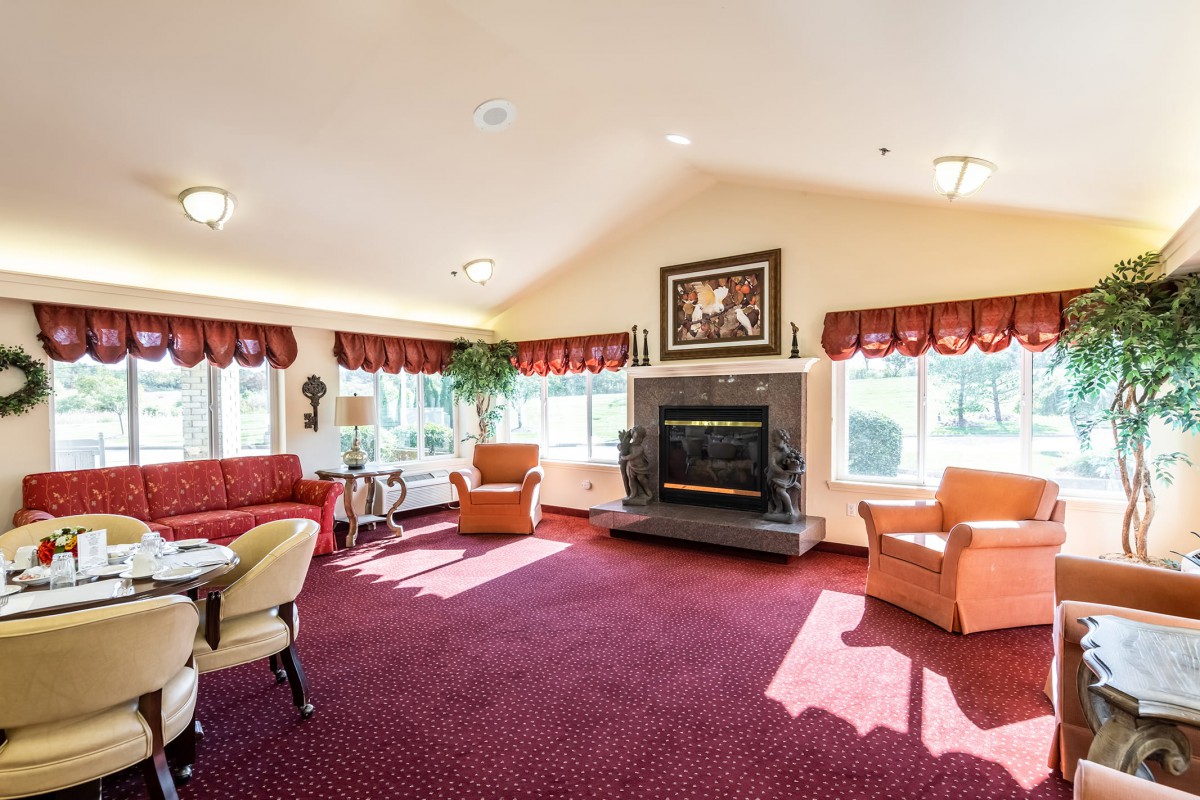 A spacious living room with a fireplace, red carpet, and multiple seating areas.
