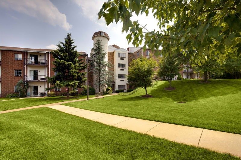 A sunny day view of an apartment complex with a unique silo feature and lush green surroundings.