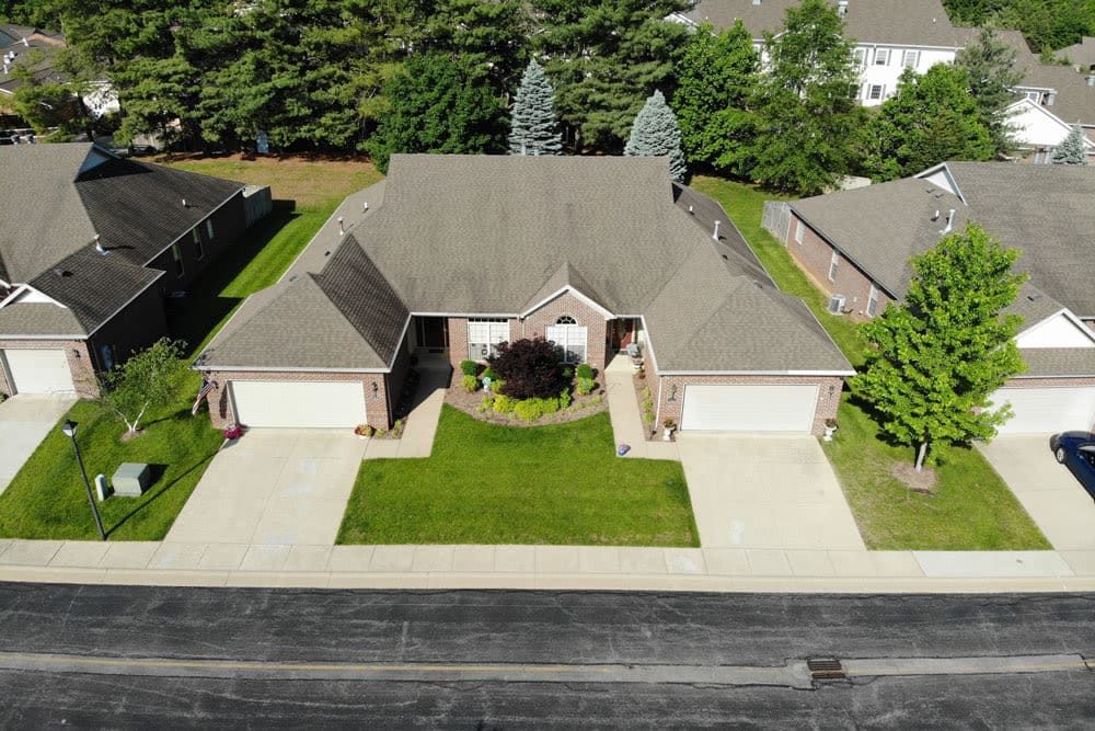 Aerial view of a duplex house with driveways and a well-maintained lawn.