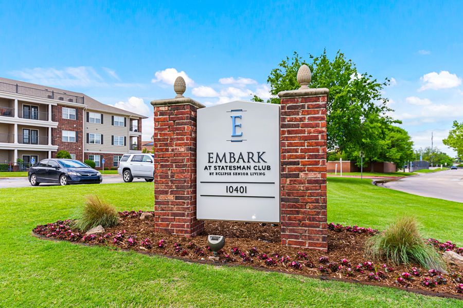Entrance sign for Embark Apartment Homes with brick pillars and landscaping.