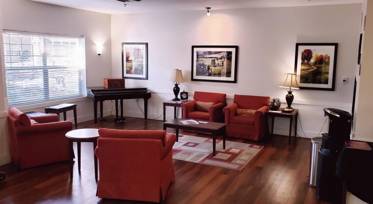 A cozy living room with red armchairs, a coffee table, and artwork adorning the walls.