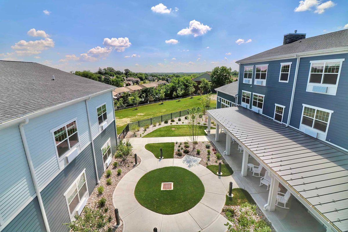 A modern courtyard surrounded by buildings with a landscaped lawn and clear blue sky.