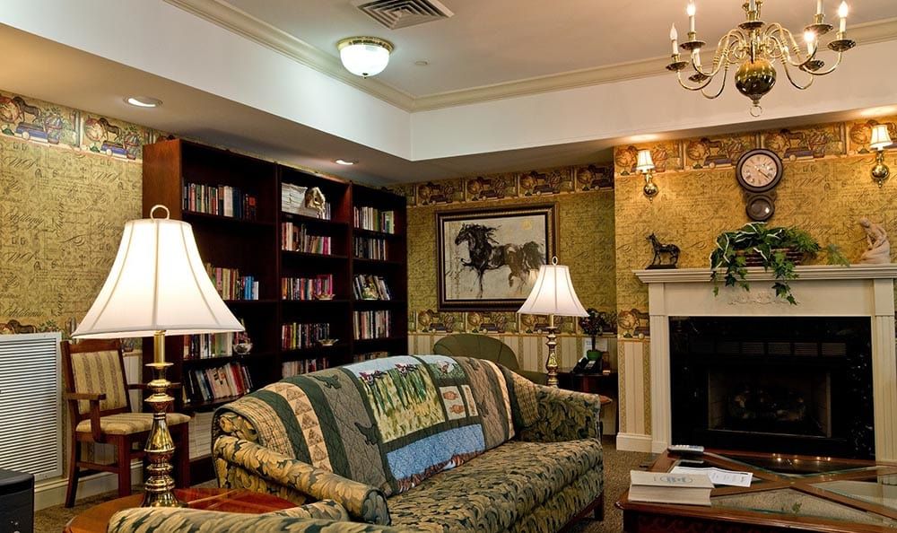 A cozy living room with bookshelves, a patterned sofa, and warm lighting.