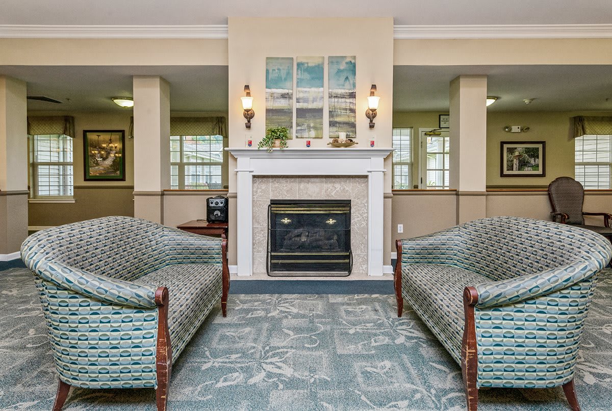 A traditional living room featuring a central fireplace, two upholstered sofas, and stylish artwork above the mantel.