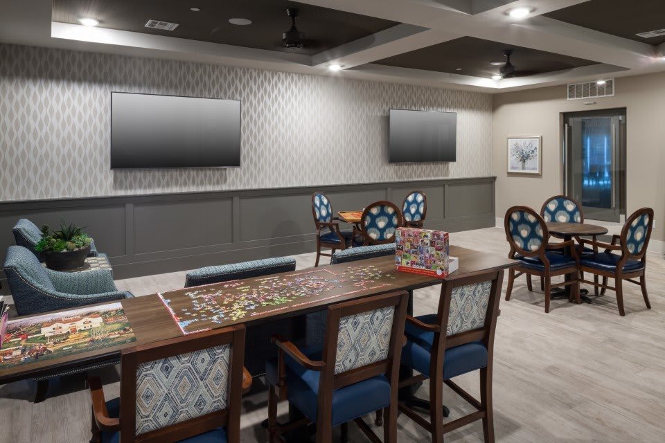 A modern game room with a puzzle on the table and wall-mounted televisions.
