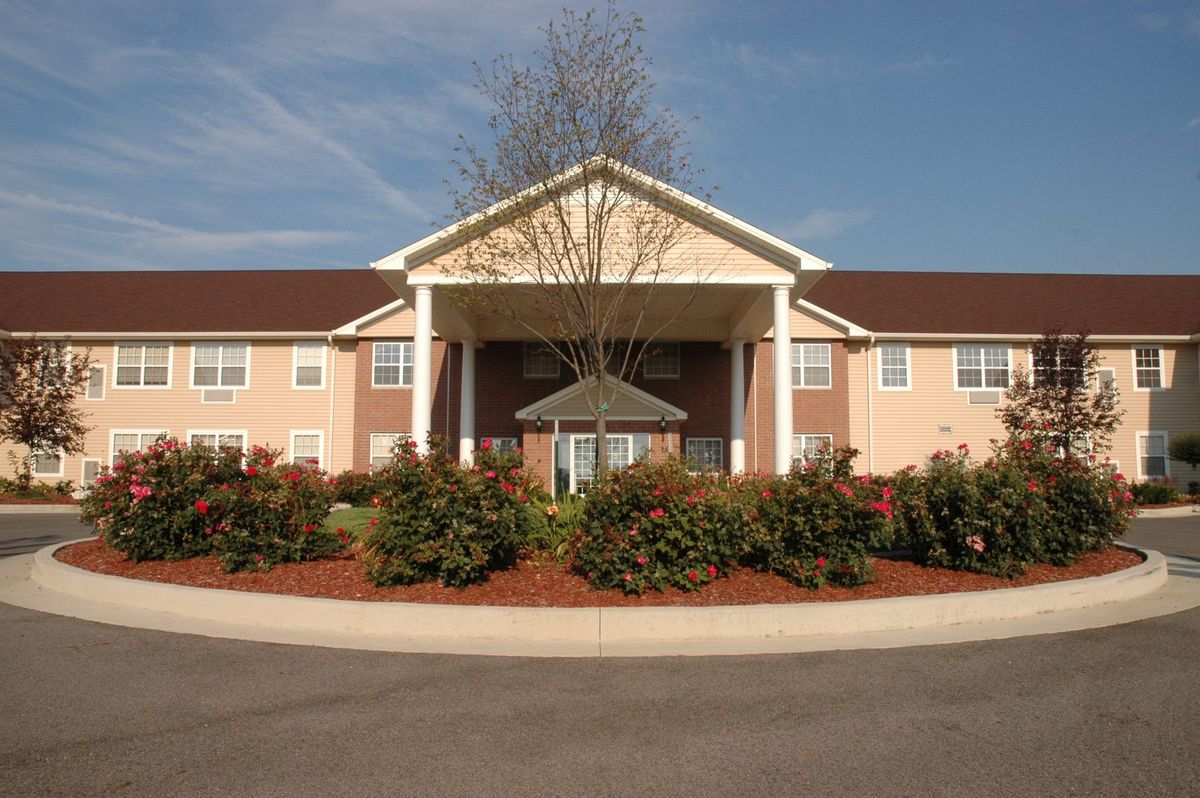 A residential building with a landscaped entrance under a clear blue sky.