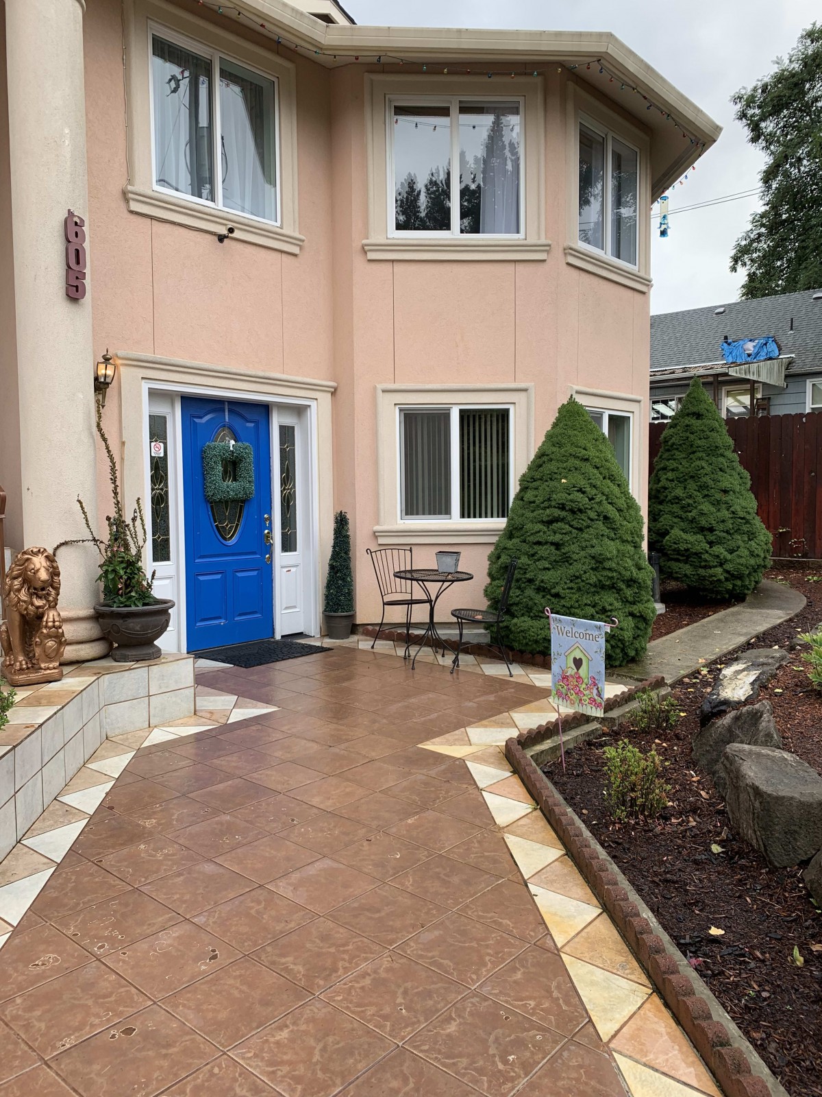 A charming house with a blue door and a neatly landscaped front yard.