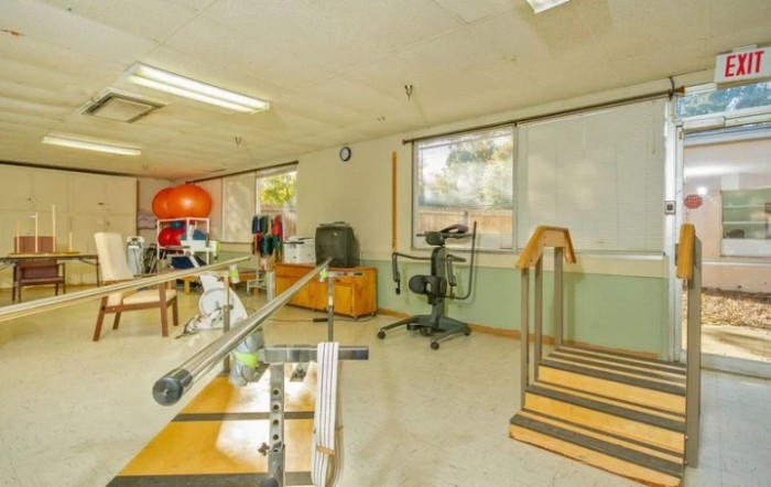 An empty rehabilitation room equipped with various exercise and therapy equipment.